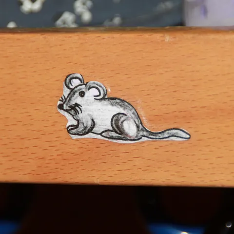 Aufkleber einer gezeichneten Maus auf einer Schrankkante.