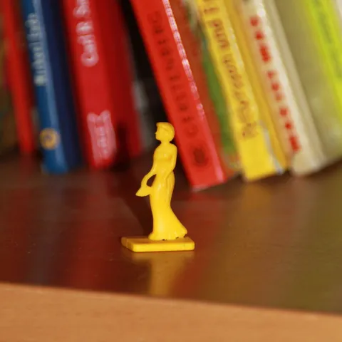 Bücherreihe in einem Regal, davor eine kleine gelbe Spielfigur.