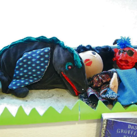Handpuppen auf der Fensterbank, daneben das Bilderbuch „Der Grüffelo“.