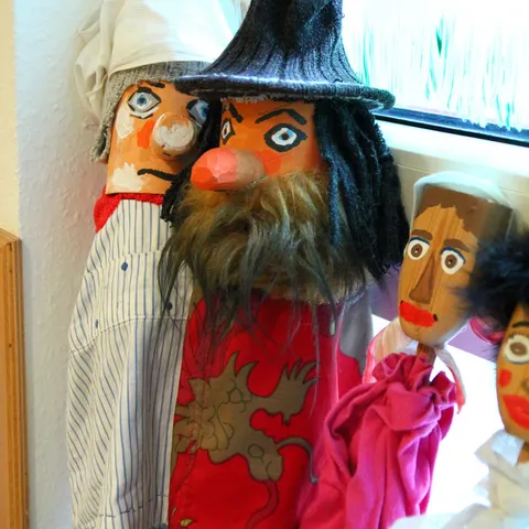 Nahaufnahme der Stabpuppen, vorn eine Figur mit Hut, Bart und rotem Umhang.
