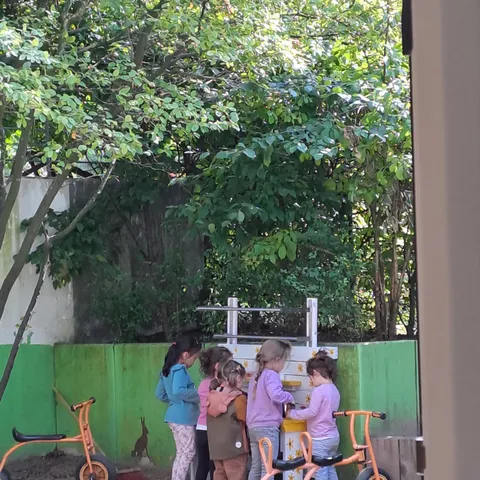 Blick aus dem Kinderladen nach draußen; im Hintergrund stehen Kinder an der neuen Matschküche.