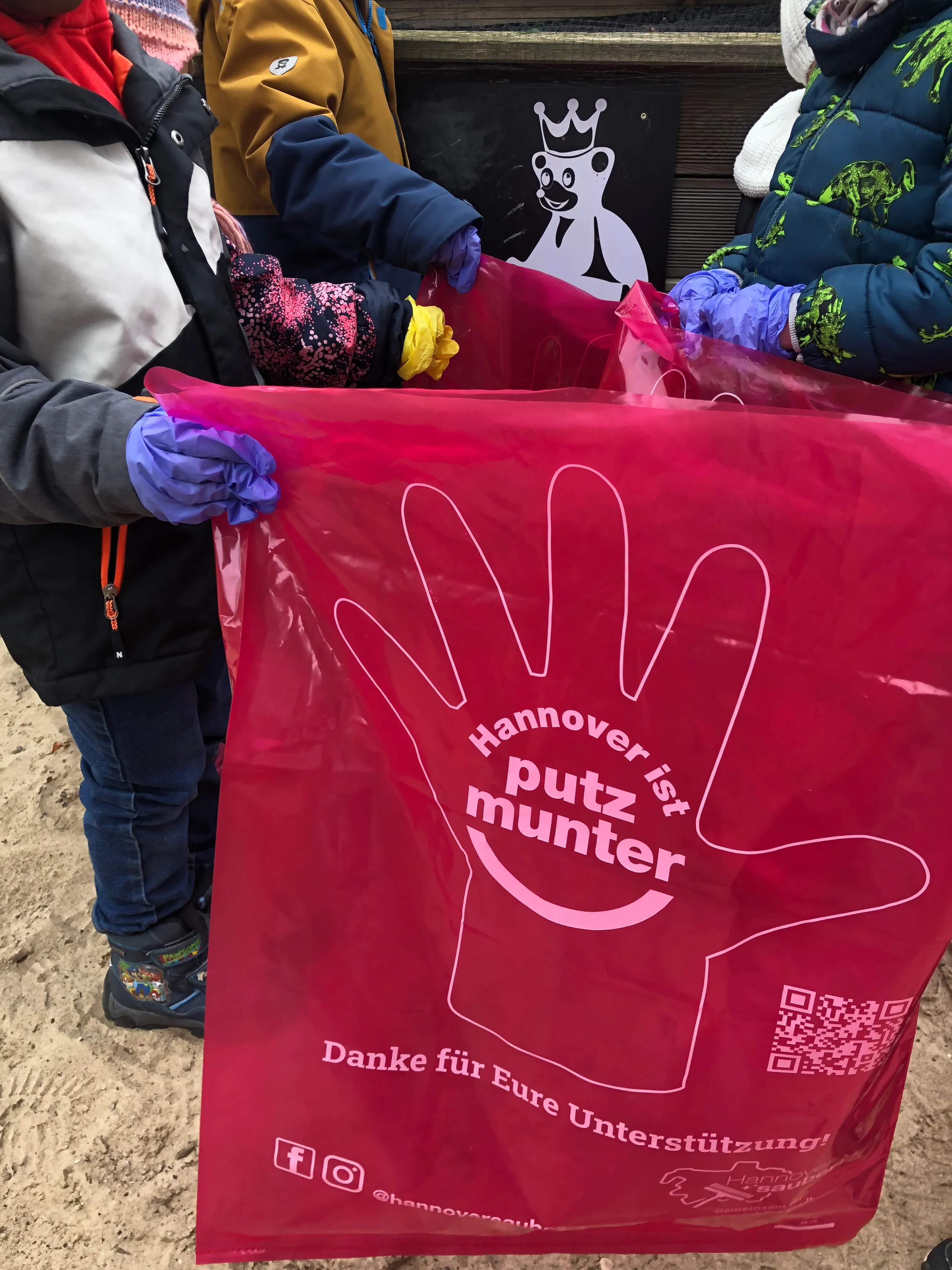 Ein Kind hält einen rosa Müllsack der Aktion „Hannover ist putzmunter“ auf.