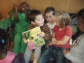 Kinder sitzen auf einem Sofa und schauen gemeinsam in ein Buch.