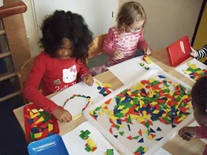 Zwei Kinder experimentieren mit geometrischen Holzbausteinen.